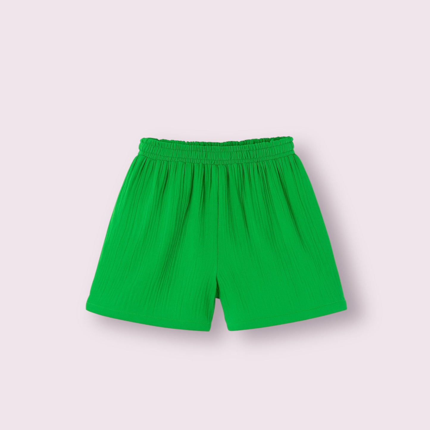 Fotografía de pantalón deportivo tipo short color verde brisa, diseño cómodo y fresco ideal para verano, con cintura elástica fruncida, imagen de prenda en plano sobre fondo liso rosa claro, moda femenina casual para tienda online.