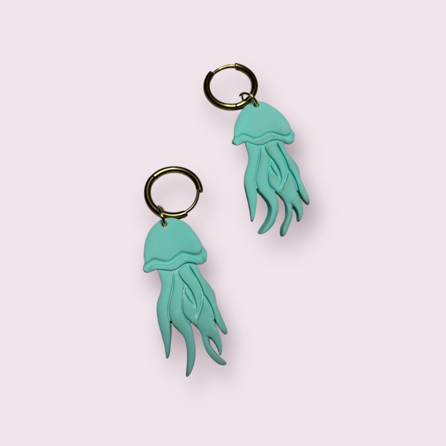 Pendientes artesanales con forma de medusa en color azul turquesa, elaborados a mano en arcilla polimérica y montados en aro dorado. Diseño original de Aroa Dedales ideal para looks frescos y marinos, perfecto como regalo único para verano o como joya original hecha en España. Complemento colorido, divertido y con movimiento para destacar cualquier outfit veraniego o bohemio.