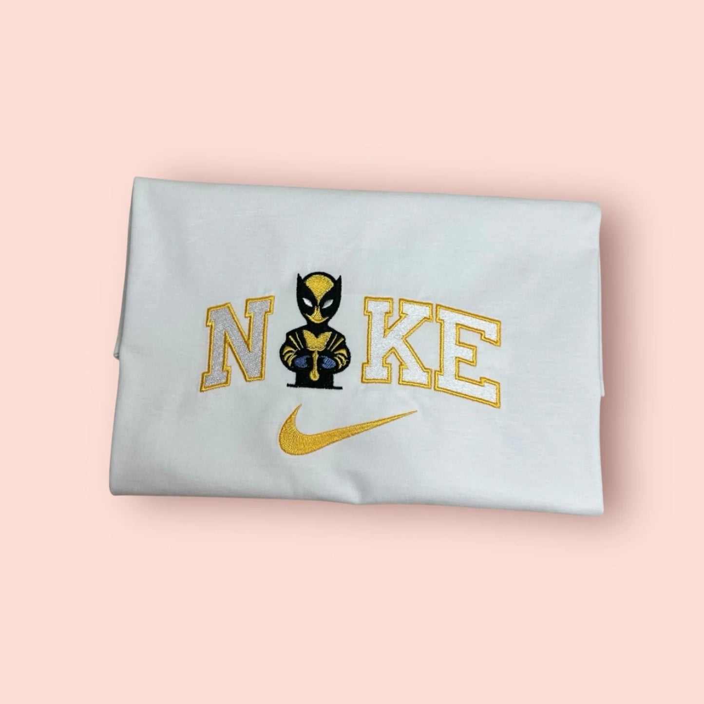 Sudadera blanca de algodón con un bordado exclusivo de Lobezno (Wolverine) luciendo su clásico traje amarillo y azul de los X-Men. El diseño muestra al personaje en estilo "chibi" con las garras fuera, integrado en el logo con letras universitarias amarillas. Ropa friki de alta calidad, ideal para fans de Logan y Marvel. La prenda perfecta para comprar en conjunto con la sudadera de Deadpool y crear el "matching outfit" más viral del año.