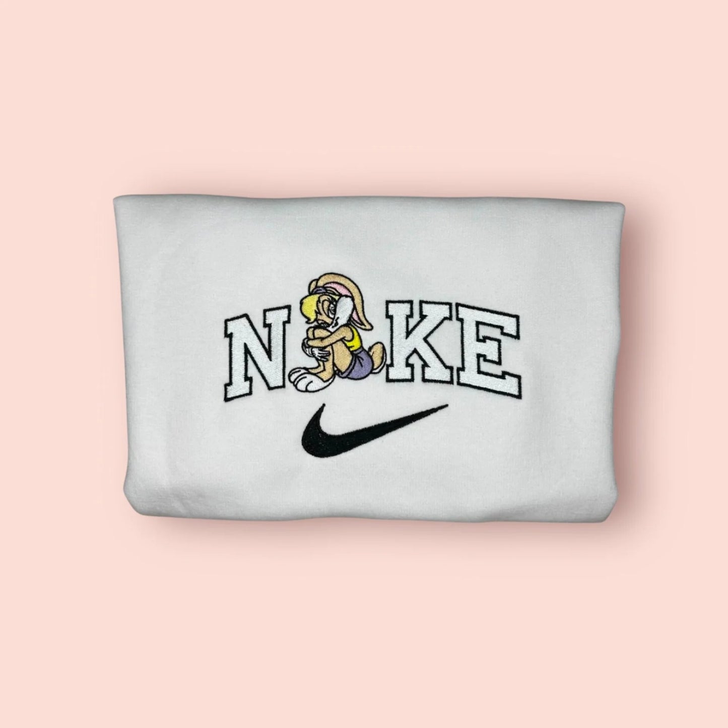 Sudadera blanca de algodón con un bordado exclusivo de Lola Bunny. El diseño muestra al personaje de Looney Tunes en una pose coqueta, integrado en letras estilo universitario. Ropa personalizada inspirada en la película Space Jam y la estética de los 90. La prenda perfecta para chicas con carácter que saben que no son una "muñeca". Cómprala junto a la de Bugs Bunny y formad el mejor equipo del Tune Squad.