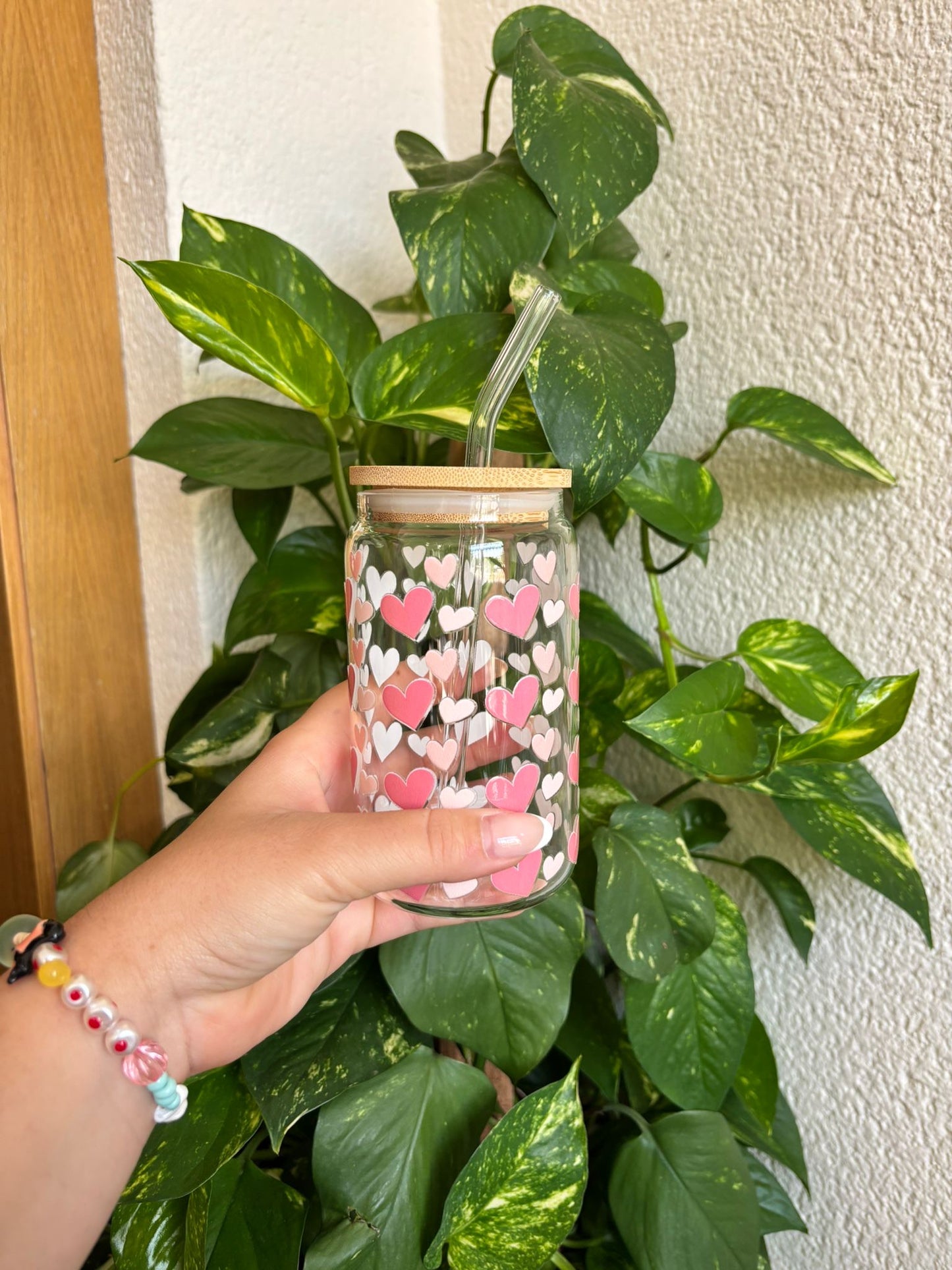 Vaso de cristal con tapa de bambú y pajita de vidrio reutilizable, decorado con estampado de corazones rosa pastel y blanco. Ideal para bebidas frías como iced coffee, batidos, té helado o agua con frutas. Diseño romántico y dulce para regalar o disfrutar cada día. Perfecto para amantes del estilo kawaii, handmade y eco-friendly.
