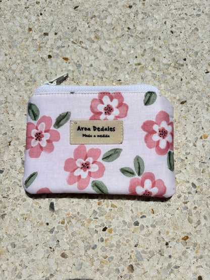 Monedero blanco con estampado de flores rosas y verdes, cierre de cremallera metálica, hecho a mano por Aroa Dedales. Ideal para uso diario o como regalo artesanal.