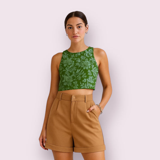 Mujer joven con bermudas corte sastre en color tierra suave, diseño elegante con cinturilla alta y pinzas, combinadas con un top floral verde, estilo sofisticado y moderno para verano 2025, moda femenina hecha a mano en España, Aroa Dedales.