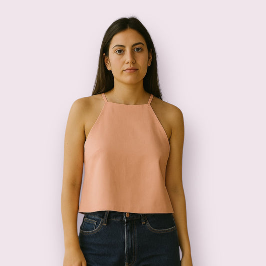 Blusa de lino en color rosa palo para mujer, con diseño elegante y escote halter, ideal para verano, ropa fresca y ligera, prenda de lino artesanal perfecta para looks casuales o sofisticados, combinada con vaqueros en imagen de modelo.