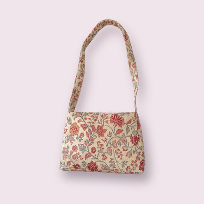 Bolso Primavera con estampado floral bordado en tonos rojizos y rosas sobre fondo beige, diseño artesanal ideal para primavera o verano. Hecho a mano por Aroa Dedales, este bolso único es perfecto para complementar outfits románticos y vintage con un toque natural y femenino