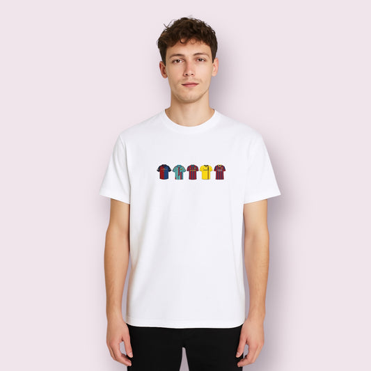 Modelo vistiendo camiseta blanca unisex con diseño impreso de camisetas icónicas del FC Barcelona en el centro del pecho. Las camisetas están representadas con efecto bordado, capturando la esencia de varias temporadas emblemáticas del club. Ideal para seguidores culés y coleccionistas de moda futbolera.