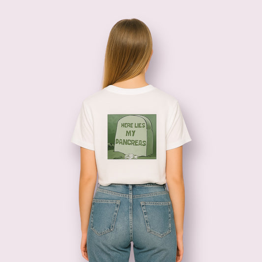 Mujer vista desde atrás luciendo la camiseta blanca "Aquí yace mi páncreas", con diseño humorístico de lápida verde, ideal para personas con diabetes tipo 1. Camiseta con mensaje divertido para diabéticos, perfecta para visibilizar la diabetes con estilo y un toque de humor. Ropa inclusiva con conciencia social y diseño original