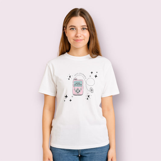 Camiseta blanca con diseño para personas con diabetes, con ilustración de bomba de insulina y mensaje "Next Diabetes Level Unlocked", modelo mujer sonriendo