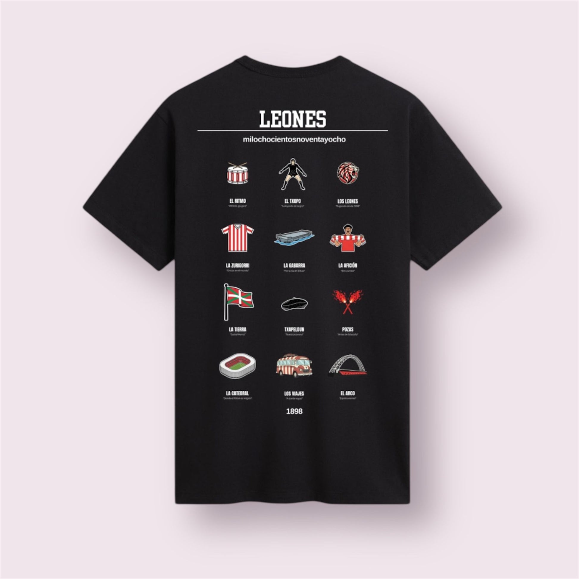 Camiseta negra edición 'Leones 1898' vista trasera. Diseño exclusivo de moda casual para aficionados del Athletic Club que celebra su filosofía única. Incluye iconos ilustrados históricos: La mítica Gabarra, 'El Txopo' Iribar, el Arco de San Mamés, el ambiente de la calle Pozas y la Ikurriña. La prenda perfecta para vestir el sentimiento zurigorri y la tradición de 1898.