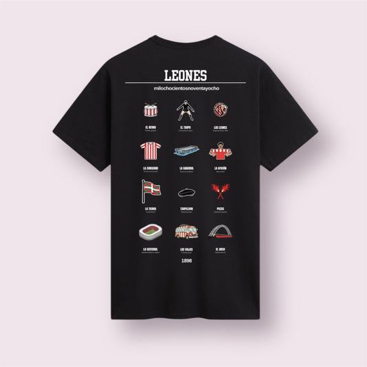 Camiseta negra edición 'Leones 1898' vista trasera. Diseño exclusivo de moda casual para aficionados del Athletic Club que celebra su filosofía única. Incluye iconos ilustrados históricos: La mítica Gabarra, 'El Txopo' Iribar, el Arco de San Mamés, el ambiente de la calle Pozas y la Ikurriña. La prenda perfecta para vestir el sentimiento zurigorri y la tradición de 1898.
