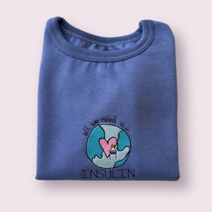 Sudadera infantil azul para niñas y niños con diseño bordado "All we need is insulin", ideal para visibilizar la diabetes tipo 1 con un mensaje positivo y tierno. Prenda cómoda, personalizada y pensada para peques con diabetes