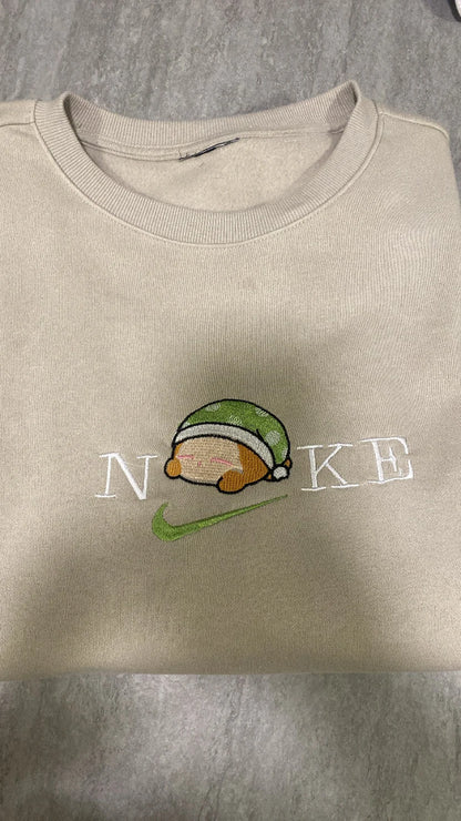 Sudadera color beige arena con un tierno bordado de Waddle Dee durmiendo. Este adorable personaje del universo Kirby lleva su gorrito verde a juego. Una prenda exclusiva para fans de Nintendo que buscan algo diferente al clásico Kirby rosa. Ideal para comprar en pack junto a la sudadera de Kirby y hacer un "matching outfit" de sueño y relax.