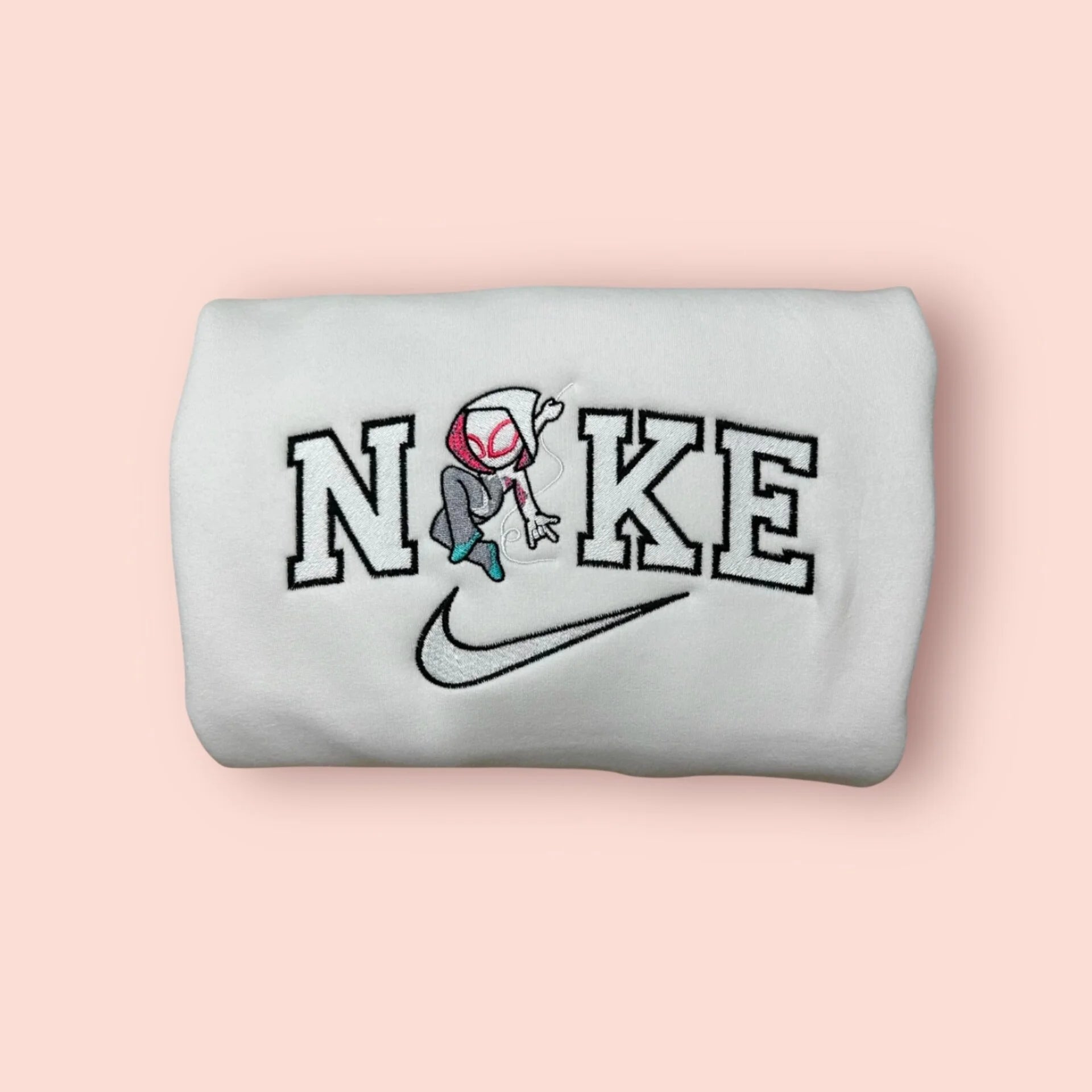 Sudadera blanca de algodón con un bordado exclusivo de Spider-Gwen (Ghost-Spider). El diseño captura la agilidad del personaje de "Across the Spider-Verse" con su capucha y traje característicos, integrado en letras estilo universitario. Ropa personalizada de Marvel, ideal para regalar a tu novia o fan del Spider-Verse. Combínala con la sudadera de Spider-Man para crear el 'matching outfit' que desafía cualquier evento canónico.