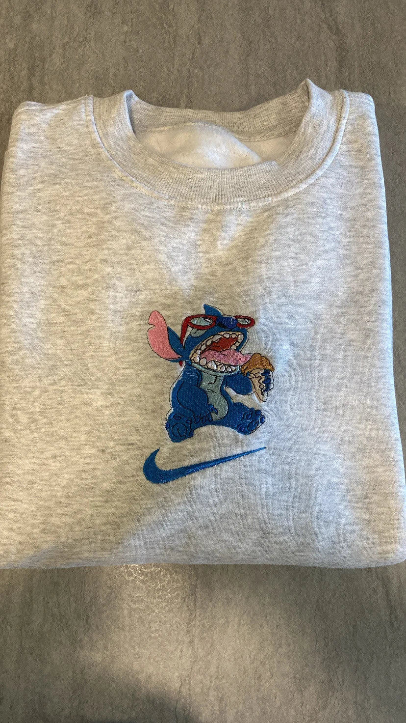 Sudadera gris con un bordado vibrante de Stitch (Experimento 626) devorando un helado. El diseño captura la energía caótica y adorable del personaje con sus gafas de sol. Una prenda imprescindible para fans de Disney que buscan un estilo divertido. La pieza clave para completar el dúo con la sudadera de Lilo y demostrar que sois los mejores "compañeros de crímenes".