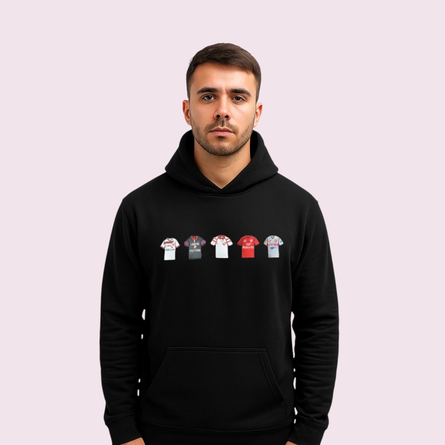 Hombre joven con sudadera negra decorada con bordado de camisetas históricas del Sevilla FC, ideal para aficionados del fútbol sevillista. Diseño original para amantes del deporte, con cinco camisetas representativas del club andaluz, perfecta como regalo personalizado para fans del Sevilla.