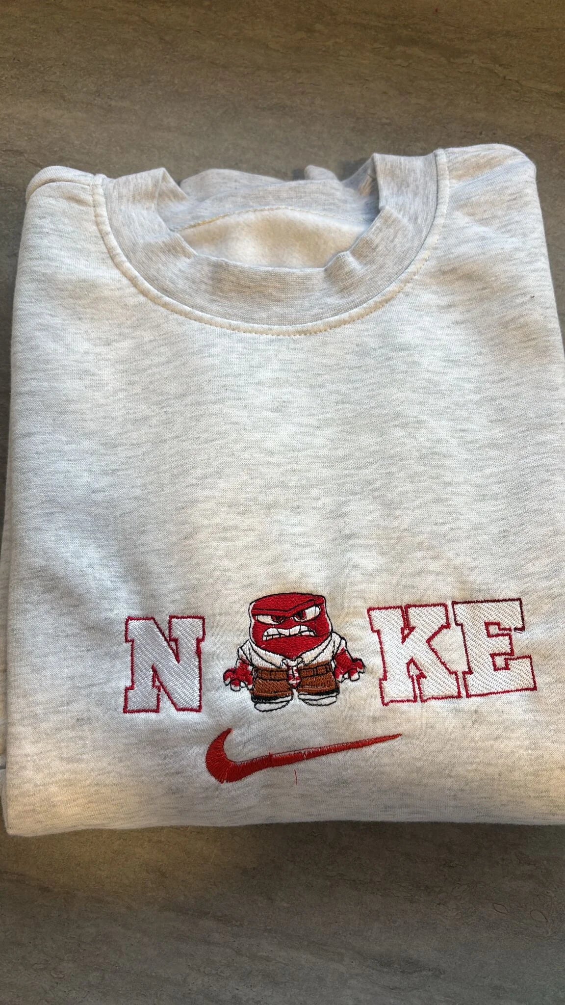 Sudadera color gris jaspeado con bordado premium del personaje Ira (Anger) de la película Del Revés (Inside Out). Diseño divertido con el personaje rojo enfadado integrado en el logo. Tejido de algodón suave y cálido. Compra esta sudadera personalizada de Ira perfecta para fans de la película que buscan ropa original y con carácter.