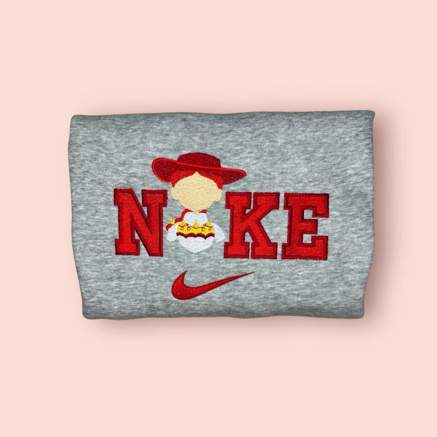 Sudadera gris jaspeado con un vibrante bordado rojo de Jessie, la vaquera de Toy Story. El diseño presenta la silueta del personaje con su icónico sombrero y trenzas sobre letras estilo universitario. Ropa personalizada ideal para chicas fans de Disney Pixar. Compra esta sudadera para combinar con el modelo de Woody y crear el outfit de pareja perfecto. Tejido suave y resistente.