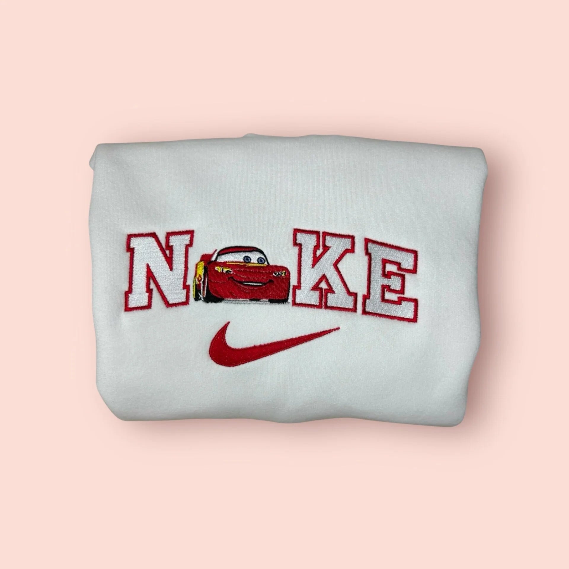 Sudadera blanca con un vibrante bordado de Rayo McQueen. El diseño en rojo intenso captura la energía del campeón de la Copa Pistón. Ropa personalizada de Cars, ideal para hombres o como regalo original para novios. ¡Kachow! Compra esta sudadera junto a la de Sally para tener el look más rápido y romántico de Radiator Springs.