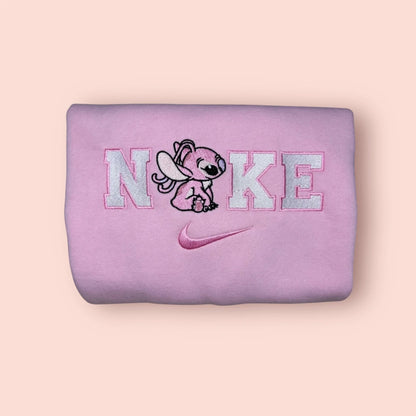 Sudadera de color rosa pastel con un bordado adorable de Ángela (Angel/Experimento 624), la novia de Stitch. El diseño muestra al personaje en una pose tierna integrado en letras estilo universitario con hilos blancos y rosas. Ropa personalizada "kawaii" de Disney, perfecta para chicas. El regalo de San Valentín ideal para combinar con la sudadera azul de Stitch.