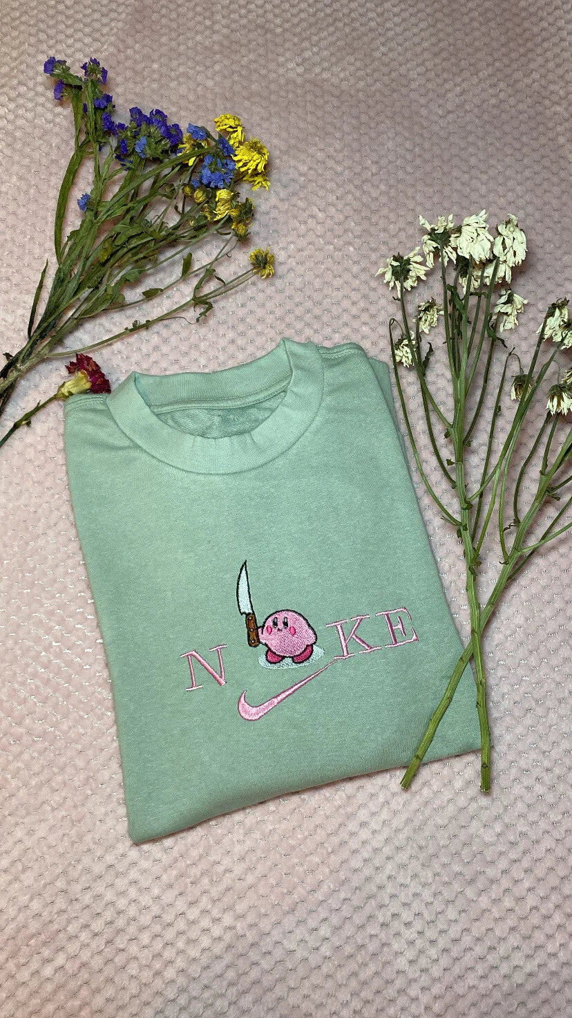 Sudadera color verde menta (mint) con el famoso meme viral de Kirby sosteniendo un cuchillo. Un diseño irónico que mezcla lo tierno con lo peligroso, bordado con gran detalle. Esta prenda es tendencia en redes sociales (TikTok/Instagram) y es el regalo perfecto para gamers con sentido del humor o para tu amigo más caótico. Estilo aesthetic y divertido en una sola prenda.