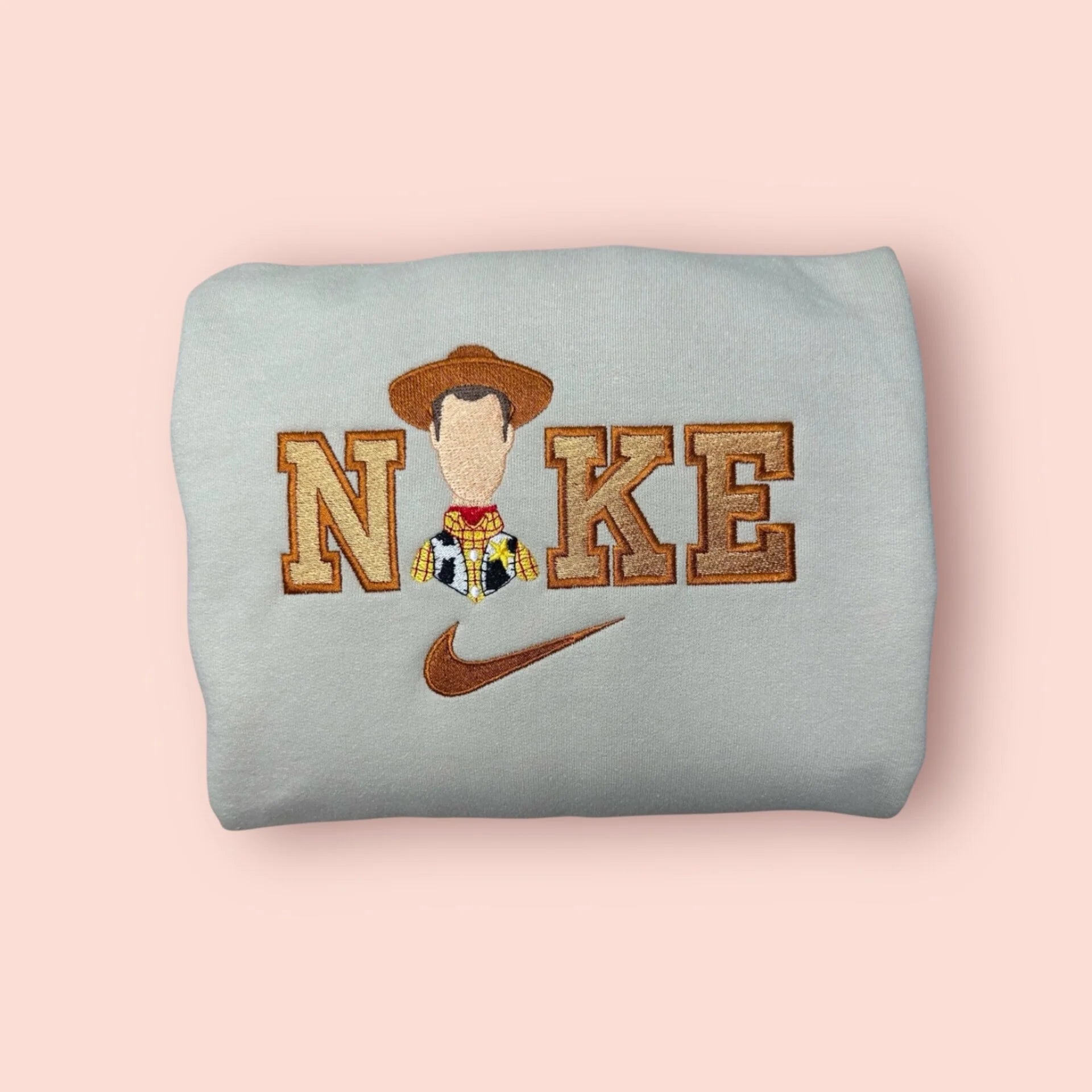 Sudadera color piedra o gris claro con bordado detallado del Sheriff Woody de Toy Story. Diseño exclusivo con tonos tierra y dorados, mostrando la placa de sheriff y el sombrero de vaquero. Sudadera personalizada de "Tu Amigo Fiel", perfecta para regalar a novios o fans de la saga. Combínala con la sudadera de Jessie para un look de "goals" en pareja. Calidad premium en cada puntada.