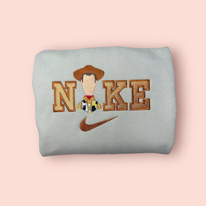 Sudadera color piedra o gris claro con bordado detallado del Sheriff Woody de Toy Story. Diseño exclusivo con tonos tierra y dorados, mostrando la placa de sheriff y el sombrero de vaquero. Sudadera personalizada de "Tu Amigo Fiel", perfecta para regalar a novios o fans de la saga. Combínala con la sudadera de Jessie para un look de "goals" en pareja. Calidad premium en cada puntada.