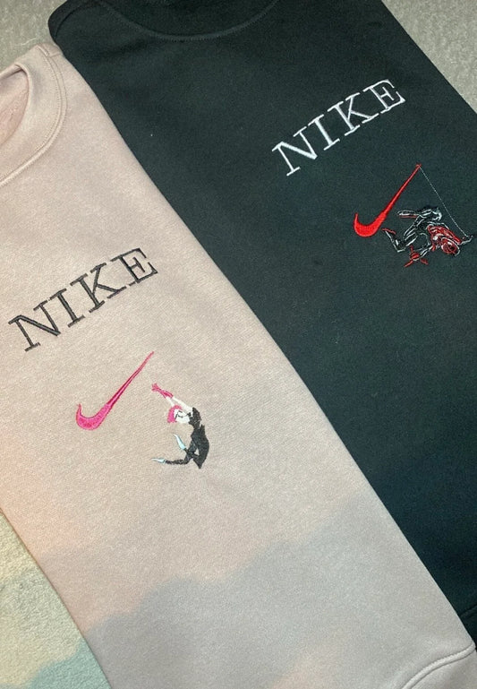 Dos sudaderas bordadas de la pareja del Spider-Verse: una sudadera beige/rosa pálido con Gwen Stacy en una pose de ballet y el logo en rosa, y una sudadera negra con Miles Morales balanceándose en el logo rojo. Diseños minimalistas y de estilo "streetwear" inspirados en la película "Across the Spider-Verse". Ropa de Marvel ideal para parejas que buscan un "matching outfit" sutil y con mucho estilo. El regalo perfecto para vuestro "evento canónico".