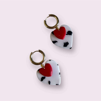 pendientes de arcilla polimérica con corazón rojo y estampado blanco y negro sobre fondo rosa