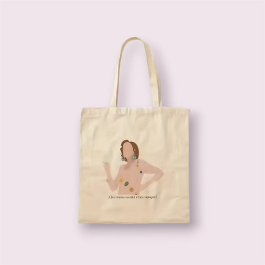 Tote bag de algodón natural con ilustración y frase icónica 'Qué mona va esta chica siempre', inspirada en la serie Aquí no hay quien viva. Diseño divertido y nostálgico ideal como regalo original para fans de la televisión española, hecha a mano en España con materiales sostenibles. Bolsa resistente, reutilizable y con mucho estilo para uso diario, compras o escapadas. Complemento eco-friendly perfecto para quienes aman la moda con guiños culturales y sentido del humor.