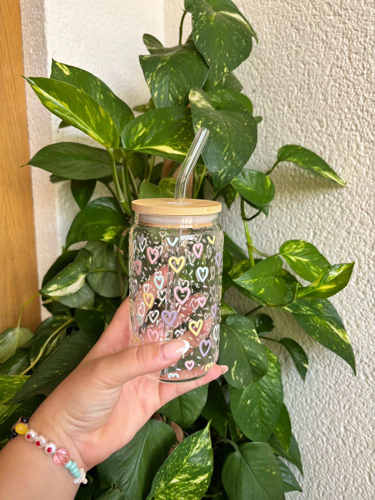Vaso de cristal decorado con corazones de colores pastel, tapa de bambú y pajita reutilizable, ideal como regalo original para personas detallistas. Perfecto para bebidas frías, smoothies o café con hielo, fabricado de forma artesanal y con un diseño encantador y alegre. Apuesta sostenible y con estilo para tu día a día o para sorprender con un detalle bonito y útil.