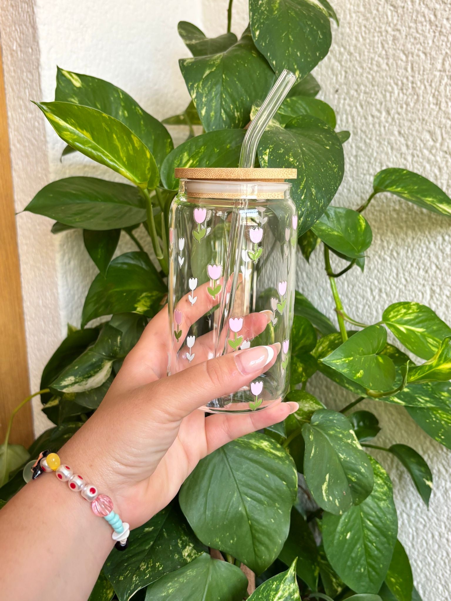 Vaso de cristal con diseño de tulipanes rosas y blancos, tapa de bambú natural y pajita de vidrio reutilizable. Ideal para bebidas frías como café con hielo, batidos, smoothies o té helado. Un accesorio ecológico, decorativo y funcional, perfecto para regalar o disfrutar en tu día a día con estilo primaveral y romántico. Hecho a mano, pensado para amantes del diseño floral y la sostenibilidad.