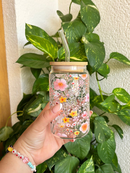 Vaso de cristal decorado con un jardín de flores silvestres en tonos rosa, amarillo y coral. Incluye tapa de bambú y pajita de vidrio reutilizable, ideal para bebidas frías como té helado, batidos, zumos o café con hielo. Diseño alegre y primaveral para disfrutar de tu bebida favorita con estilo sostenible. Perfecto como regalo hecho a mano para amantes de las flores, la naturaleza y el diseño artesanal.